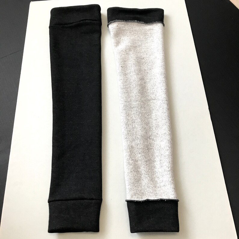 Puede incluir: Dos calentadores de brazo. Uno es negro liso, el otro es gris jaspeado. Ambos tienen un pu&ntilde;o negro en la parte superior e inferior. Los calentadores de brazo est&aacute;n hechos de un material suave y el&aacute;stico.