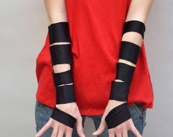 May include: A pair of black arm warmers featuring multiple horizontal fabric bands that wrap around the forearms, leaving sections of skin exposed between each band. The arm warmers extend from the upper forearm down to the base of the fingers.