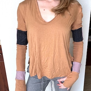 May include: A long-sleeved, brown, v-neck shirt with black and pink striped detailing on the cuffs.