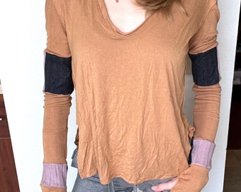 May include: A long-sleeved, brown, v-neck shirt with black and pink striped detailing on the cuffs.