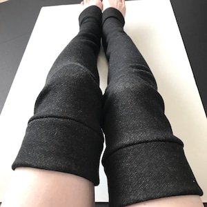 Puede incluir: Calentadores de piernas de color gris oscuro con un pu&ntilde;o doblado en el tobillo. Los calentadores de piernas est&aacute;n hechos de una tela suave y texturizada. La imagen muestra los calentadores de piernas desde las rodillas hacia abajo.