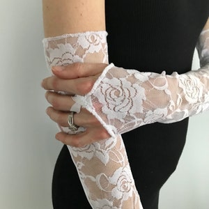 May include: White lace elbow length gloves with a floral pattern. The gloves are made of a sheer fabric and have a delicate, feminine look.