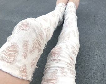May include: White lace leg warmers with a distressed, ripped look. The leg warmers are made of a soft, stretchy fabric and are perfect for adding a touch of style to any outfit.