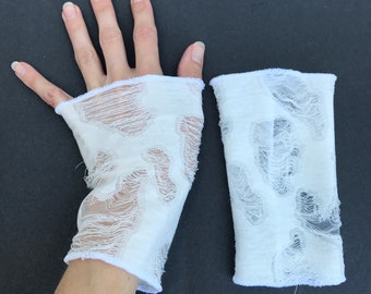 May include: A pair of white fingerless gloves with a distressed, ripped, and frayed design. The gloves are made of a soft, lightweight fabric.