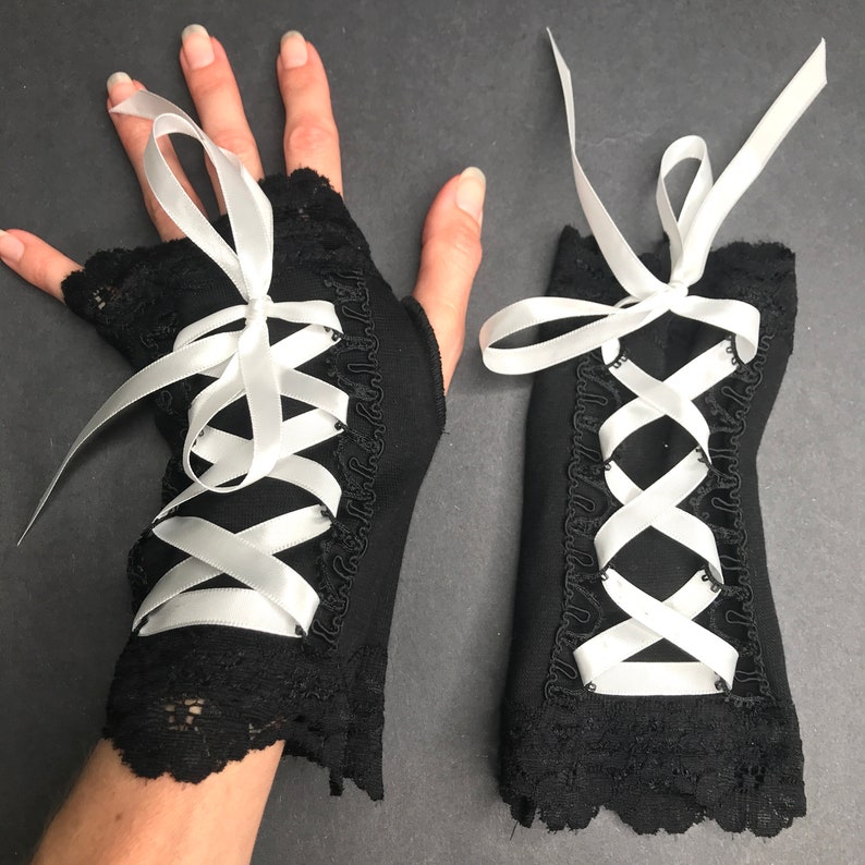 May include: A pair of black fingerless gloves with white satin ribbon lacing and black lace trim.