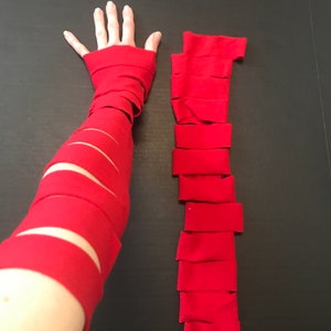 May include: A red fabric arm cuff is shown on a person's arm. The cuff is made of strips of fabric that are sewn together. A separate image shows the strips of fabric laid out flat.
