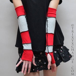 May include: Red and gray fingerless arm warmers. The arm warmers are made of fabric and feature a patchwork design with alternating red and gray sections. The seams are visible, and the wrist area is open.