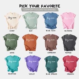 K&ouml;nnte beinhalten: Eine Auswahl an Comfort Colors T-Shirts in verschiedenen Farbt&ouml;nen, jeweils mit dem Text "boy mom" in Schreibschrift. Farben sind Elfenbein, Bay, Blue Jean, Blossom, Moss, Yam, Espresso, Pepper, Seafoam, Violett, Blue Spruce und Crimson.