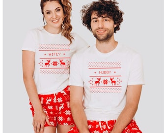 May include: Matching white t-shirts and red shorts with a Christmas theme. The shirts have the words "Wifey" and "Hubby" with reindeer and snowflake designs. The shorts are red with white snowflake patterns.