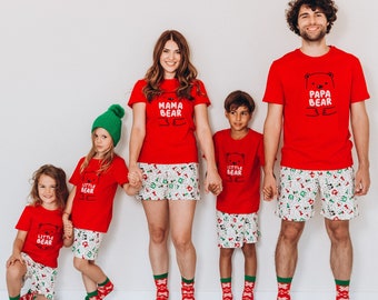 May include: A family of five wearing matching red and white pajamas with bear graphics. The pajamas have the text "Mama Bear", "Papa Bear", and "Little Bear" printed on them.