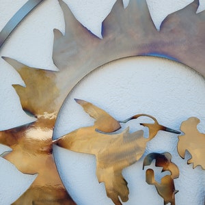 Peut inclure: Une sculpture murale en m&eacute;tal repr&eacute;sentant un colibri en vol, avec un motif de soleil derri&egrave;re lui. Le colibri est repr&eacute;sent&eacute; dans une couleur dor&eacute;e, tandis que le soleil est un m&eacute;lange de couleurs dor&eacute;es et iris&eacute;es.