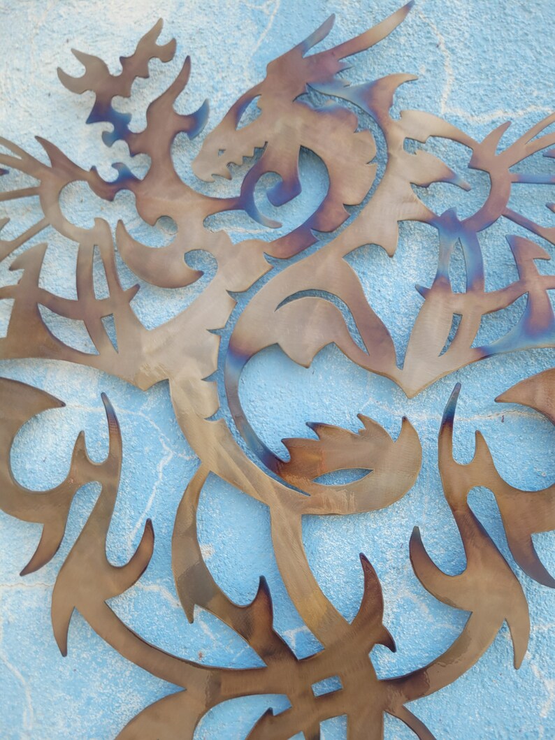 May include: A metal dragon sculpture with intricate details, cut out in a stylized design. The dragon is brown with a blue iridescent sheen, and is mounted on a blue wall.