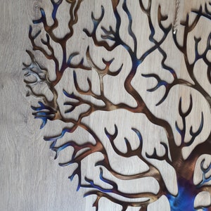 K&ouml;nnte beinhalten: Eine Wandskulptur aus Metall, die einen Baum mit einem Farbverlauf von Blau, Braun und Gold darstellt. Der Baum besteht aus d&uuml;nnem Metall und hat ein filigranes, kompliziertes Design.