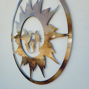 May include: A circular metal wall art piece with a sunburst design in gold and brown tones. The sunburst is centred in a circle with a silhouette of three birds inside.