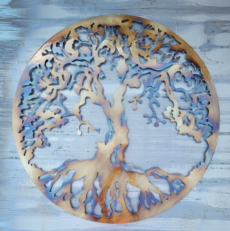 Op de afbeelding: Een cirkelvormig metalen wandkunstwerk dat een boom met ingewikkelde takken en wortels voorstelt. De boom is gemaakt van metaal en heeft een rustieke, verweerde uitstraling. De achtergrond is lichtblauw.