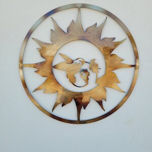 Peut inclure: Une d&eacute;coration murale en m&eacute;tal en forme de soleil avec un colibri et une fleur &agrave; l'int&eacute;rieur. Le soleil est en m&eacute;tal dor&eacute; et a un aspect rustique.