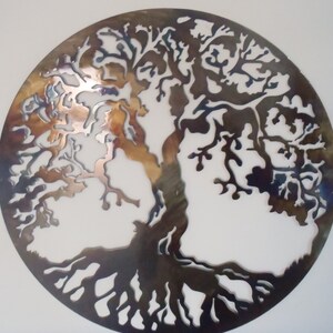 Op de afbeelding: Een cirkelvormige metalen wanddecoratie die een levensboom met ingewikkelde takken en wortels afbeeldt. Het metaal is donkerbruin van kleur met een metallic glans.