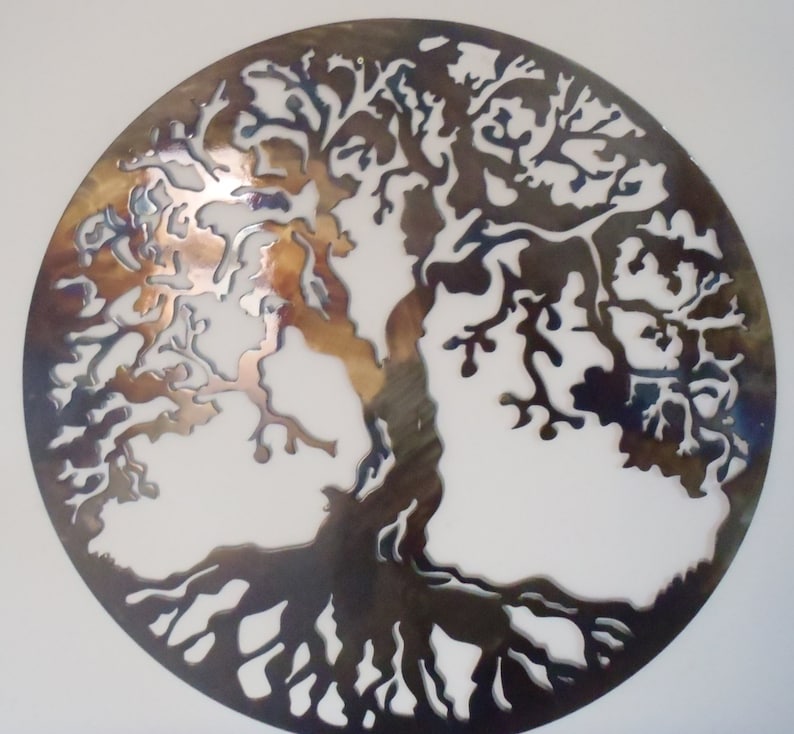 Op de afbeelding: Een cirkelvormige metalen wanddecoratie die een levensboom met ingewikkelde takken en wortels afbeeldt. Het metaal is donkerbruin van kleur met een metallic glans.