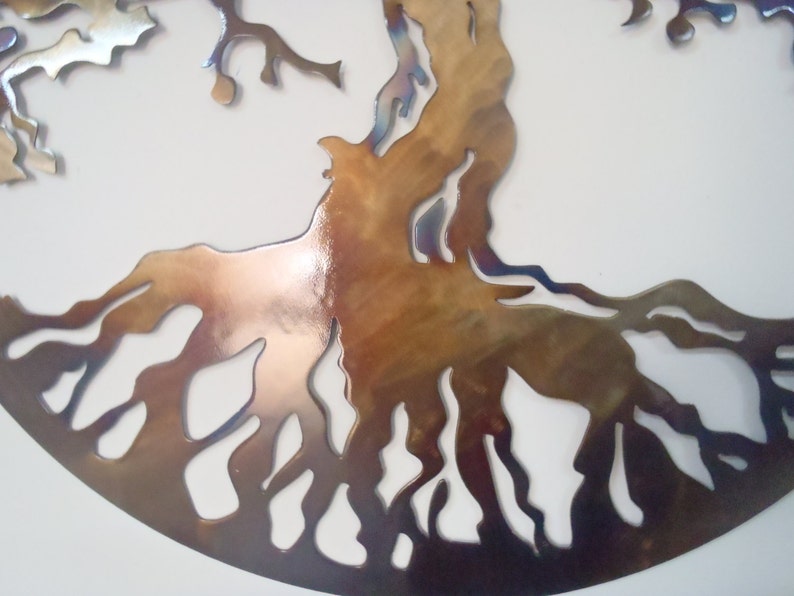 Op de afbeelding: Een metalen wandsculptuur van een boom met ingewikkelde wortels en takken. De sculptuur is gemaakt van een metalen materiaal met een bruine en iriserende afwerking.