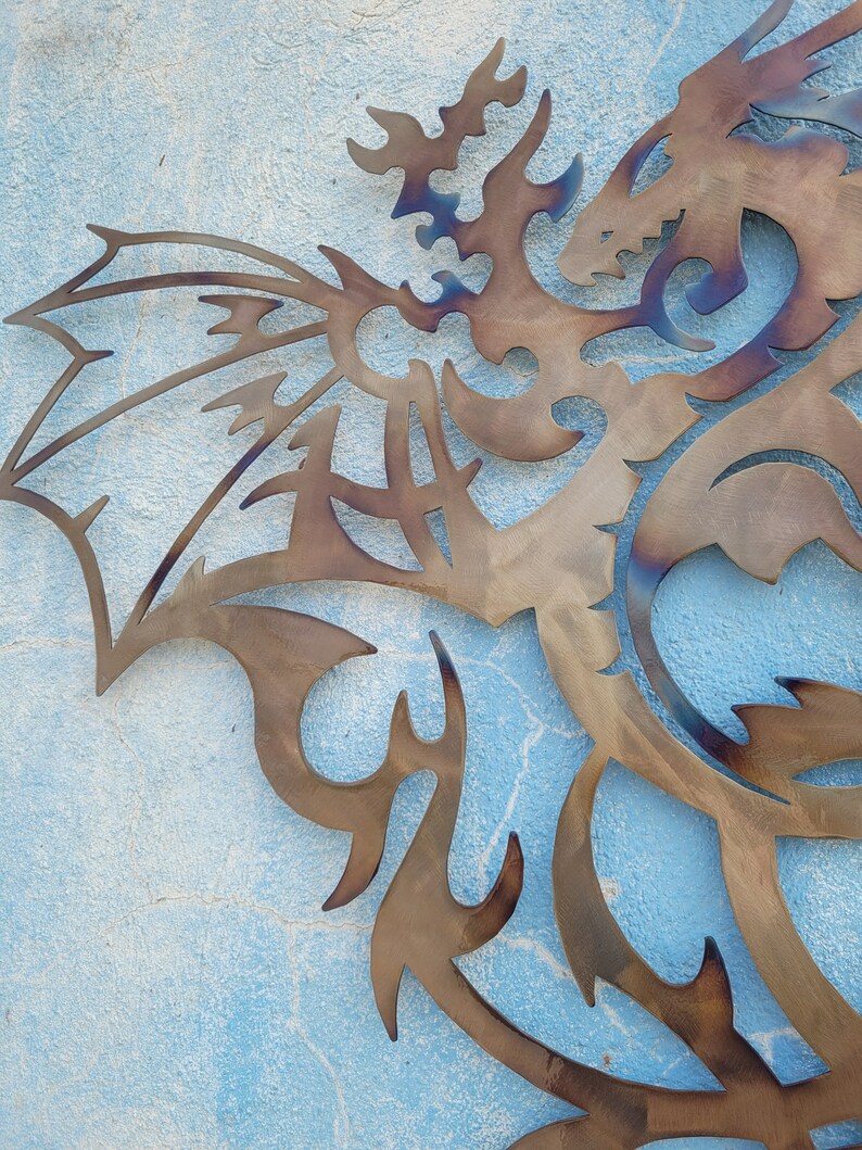May include: A metal dragon sculpture with intricate details, cut out in a brown color, against a blue background.