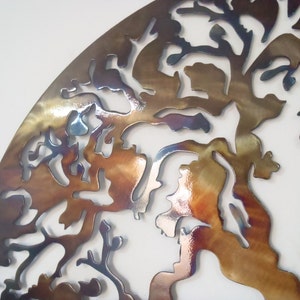 Op de afbeelding: Een metalen wandsculptuur in de vorm van een boom met een bruine, gouden en blauwe iriserende afwerking.