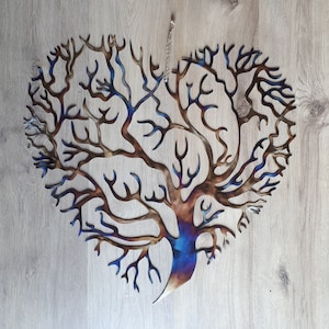 K&ouml;nnte beinhalten: Ein herzf&ouml;rmiger Wandbehang aus Metall in Form eines Baumes mit einem Farbverlauf von Blau, Lila und Braun. Der Baum hat viele &Auml;ste und ist aufwendig gestaltet.