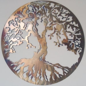 Op de afbeelding: Een cirkelvormige metalen wanddecoratie die een levensboom met ingewikkelde takken en wortels voorstelt. Het metaal heeft een geborstelde afwerking met een regenboogkleurige, iriserende glans.