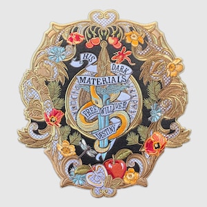 May include: Embroidered patch with a gold and black design. The center features a snake wrapped around a sword with the text "His Dark Materials Free Will Over Destiny".