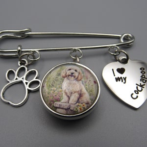 May include: Silver brooch with a paw print charm, a round charm with a picture of a Cockapoo dog, and a heart charm with the text "I love my Cockapoo".