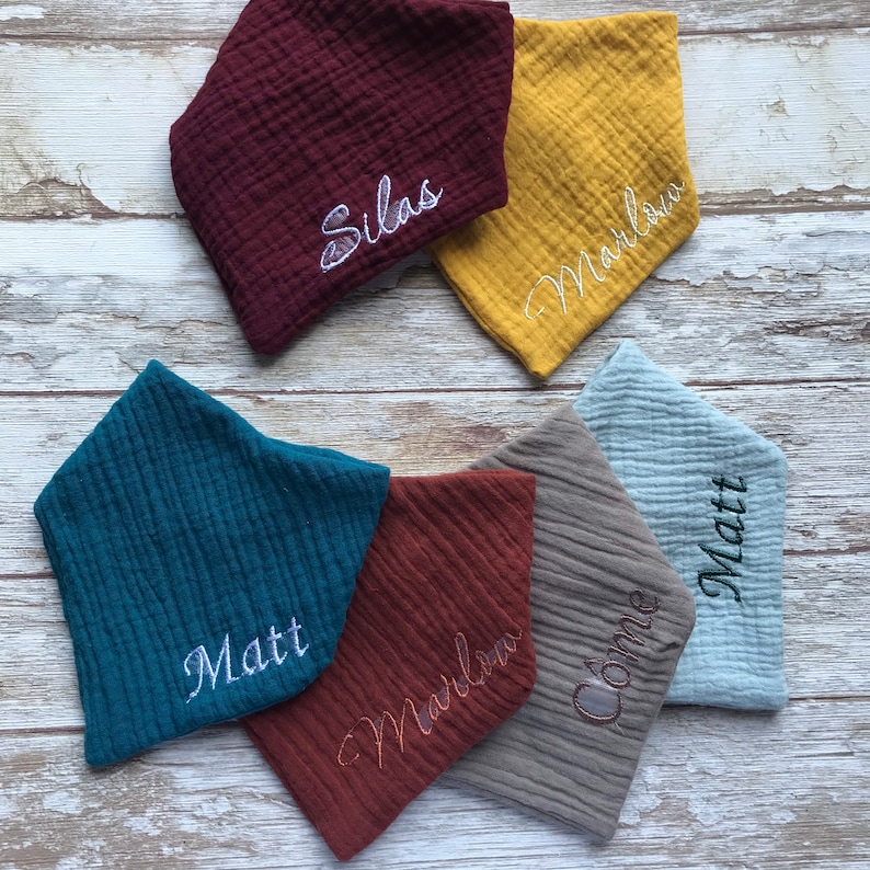 May include: Six personalized baby bibs in various colors and fabrics. The bibs are embroidered with the names Silas, Marlow, Matt, Marlow, Connie, and Matt.