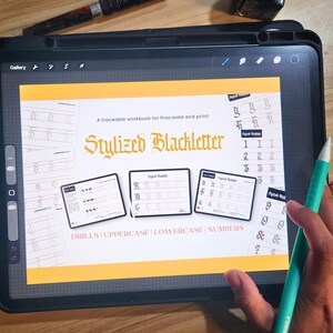 May include: A digital workbook on a tablet screen, titled "Stylized Blackletter." The workbook includes drills for uppercase, lowercase, and numbers. A teal stylus rests on the screen. The tablet is on a wooden surface.