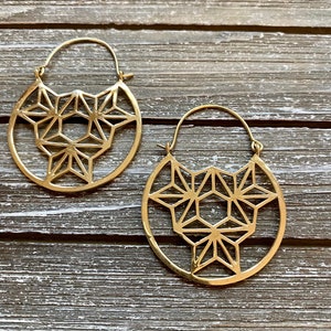 May include: A pair of gold hoop earrings with a geometric star design.