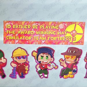 May include: A rectangular sticker with the text "I'D RATHER BE PLAYING THE AWARD WINNING HAT SIMULATOR TEAM FORTRESS 2" above five smaller character stickers. The characters include a soldier, engineer, scout, sniper, and spy in a chibi style.