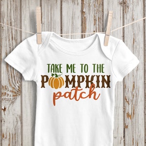 Może przedstawiać: Biały śpioszek dla niemowlęcia z napisem "Take me to the pumpkin patch" w kolorze zielonym, brązowym i pomarańczowym. Mały pomarańczowy dyni z zieloną łodygą znajduje się w środku tekstu.