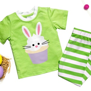 May include: Green and white striped pajamas with a green short-sleeved shirt featuring a white bunny cupcake graphic.