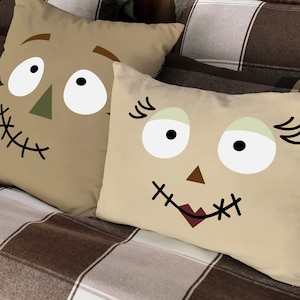 May include: Two beige throw pillows with stitched-on faces. One pillow has a brown nose, brown eyebrows, and a stitched-on mouth. The other pillow has a brown nose, black eyelashes, and a red stitched-on mouth.
