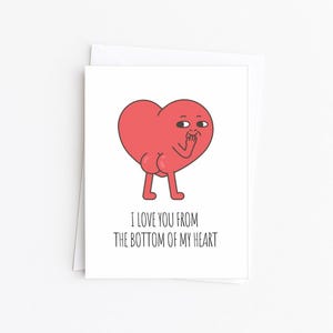 May include: A white greeting card with a red heart-shaped character covering its mouth. The character has legs and a rear end. The text "I LOVE YOU FROM THE BOTTOM OF MY HEART" is printed below the illustration.