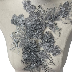 May include: Silver floral applique with sequins and rhinestones. This delicate embellishment is perfect for adding a touch of sparkle to clothing, accessories, or home decor projects.