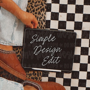 May include: A black tablet screen displaying the white cursive text Simple Design Edit with a white stylus resting along the bottom edge. The tablet is positioned against a background featuring a black and white checkered pattern and leopard print.