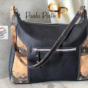 May include: Black cork and brown floral patterned shoulder bag with a zippered pocket and a long adjustable strap. Paula Pinto is written on the bag.