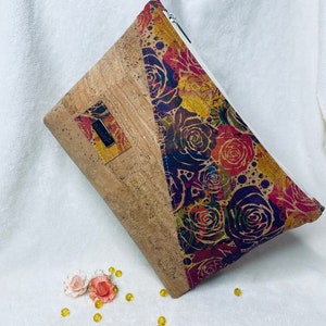 May include: A cork and fabric zipped pouch with a floral pattern in shades of red, purple, and yellow. The pouch has a cork flap with a small leather tag.