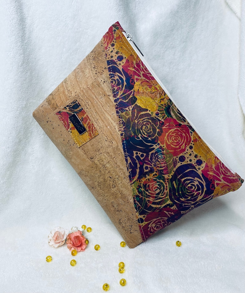 May include: A cork and fabric zipped pouch with a floral pattern in shades of red, purple, and yellow. The pouch has a cork flap with a small leather tag.