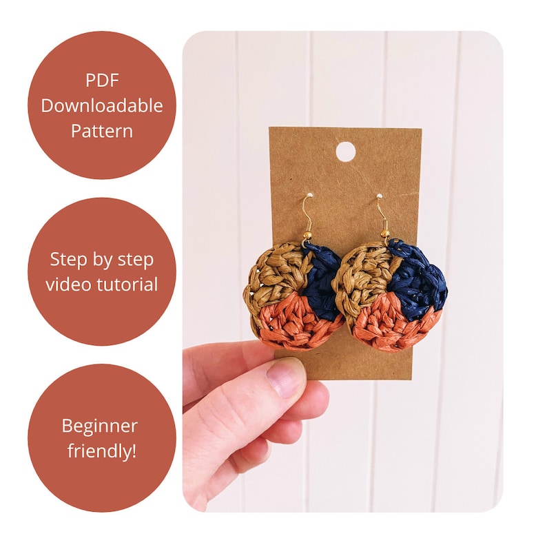 May include: A pair of crocheted earrings with a brown, orange, and blue color scheme. The earrings are hanging from a brown card.