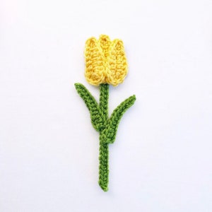 Könnte beinhalten: Eine gehäkelte gelbe Tulpe mit grünen Blättern und Stiel.
