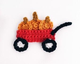 Puede incluir: Un carro rojo de crochet con ruedas negras y un centro blanco. El carro está lleno de cuatro calabazas naranjas de crochet.