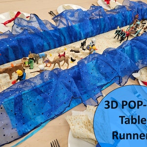 May include: A blue 3D pop-up table runner with a ruffled design and scattered silver dots. The runner is decorated with toy figurines and text that reads "3D POP-UP Table Runner!"