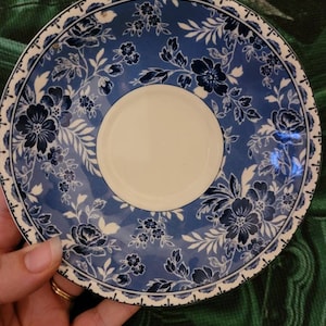 May include: A blue and white floral patterned saucer with a white centre. The saucer has a scalloped edge.