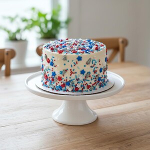White frosted 6 inch round cake covered in red white and blue rocket ship sprinkles on a white cake stand. Luxury Birthday Sprinkles Custom Sprinkles Cake Sprinkles Cupcake Décor Rocket Birthday Décor Space Sprinkles