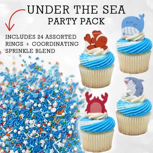 Puede incluir: Un "Pack de fiesta bajo el mar" con cupcakes cubiertos con anillos de criaturas marinas, glaseado azul y una mezcla de chispas. El paquete incluye 24 anillos variados y chispas coordinadas. Los cupcakes tienen una base blanca y glaseado azul.