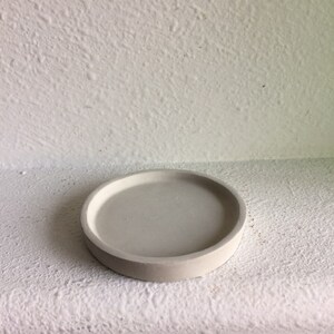 May include: A white round concrete coaster with a smooth surface.
